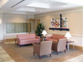 a lobby with pink couches and chairs and a painting on the wall at McCormack House at Forest Park Southeast Senior apartments in St.  Louis, MO