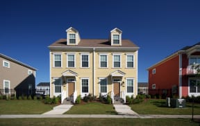 a yellow house with a brown roof and a sidewalk in front of it