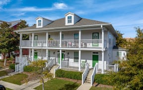 a white house with green doors and a porch
