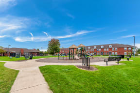 a park with a playground and benches in front of a building at Horace Mann apartments and townhomes in Gary, IN