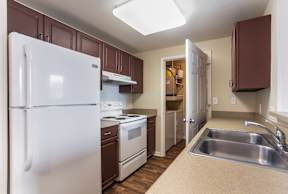 A kitchen with brown cabinets and a white refrigerator.