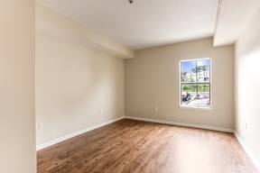 Empty room with wooden floor and a window showing an outdoor scene.