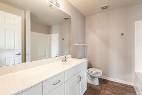 A white bathroom with a toilet, sink, and mirror.