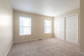 A room with two windows and a carpeted floor.