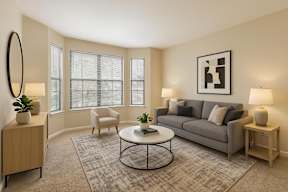 A living room with a grey couch, a white coffee table, and a large mirror on the wall.