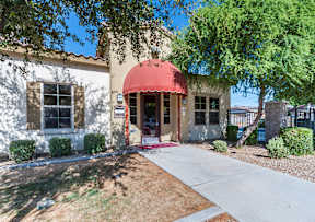 A white building with a red awning and a small porch.