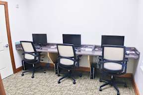 A room with four chairs and two laptops on a table.