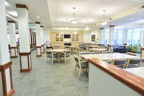 A large room with tables and chairs and a counter.
