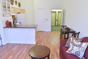 A kitchen with a white fridge and a red couch with a pillow on it.
