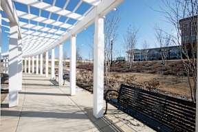 A black bench under a white and blue striped awning.
