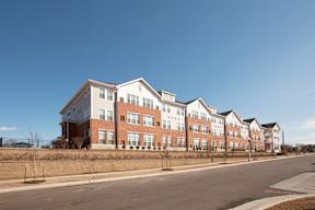 A row of red brick apartment buildings with white trim and windows.