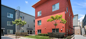 a red apartment building with a sidewalk in front of it