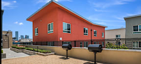the back of a red apartment building with a BBQ area with two grills at MacArthur Park Apartments