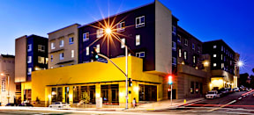 MacArthur Park Apartments building at night; a blue and yellow modern structure