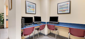 a computer room with four computers and chairs at MacArthur Park Apartments