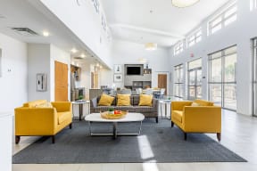 a community room with yellow couches and chairs and a table at Marrero Commons Apartments & Townhomes