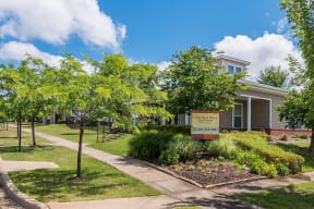 a sidewalk in front of a leasing office with trees and a sign Cumberland Manor and Metropolitan Village Apartments and Townhomes in Little Rock, AR.