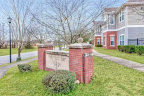 A sign that says Metropolitan Village stands in front of a brick building.