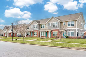A row of houses with a blue sky and white clouds above them.