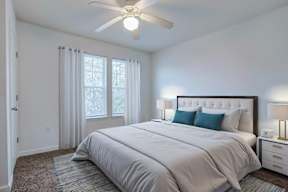 A bedroom with a large bed and a ceiling fan.