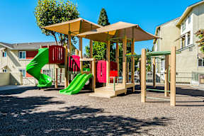 A playground with a green slide and a red and pink slide.