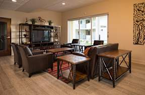 A living room with a brown leather couch, a wooden coffee table, and a television on a wooden stand.
