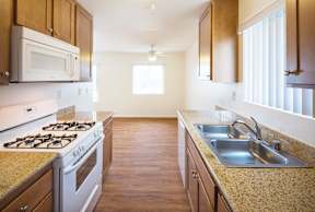 A kitchen with a stove, sink, and cabinets.