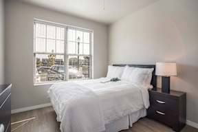A bedroom with a large bed and a window overlooking a street.