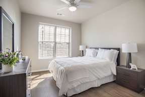 A bedroom with a bed, nightstand, and a ceiling fan.