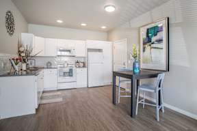A kitchen with white cabinets and a wooden floor.