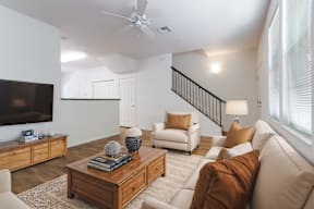 A living room with a white couch, a wooden coffee table, and a flat-screen TV.