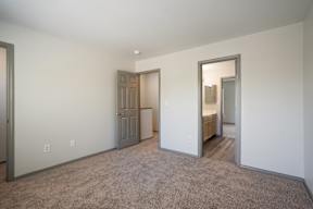 A room with a carpeted floor and a door on the left side.