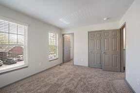 A room with a carpeted floor and a large window with blinds.