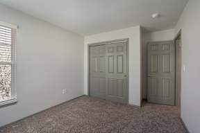 A room with a carpeted floor and two doors.