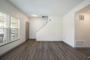 A room with a staircase and a window with blinds.