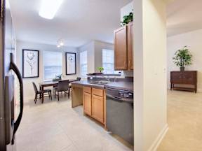 A kitchen with a black fridge and wooden cabinets.