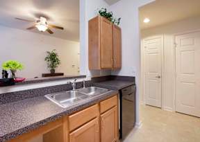 A kitchen with a sink, a stove, and a fan.
