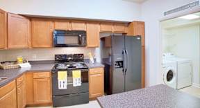 A kitchen with a black stove top oven and a black microwave above it.