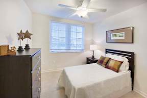 A bedroom with a bed, dresser, and a ceiling fan.
