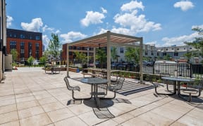 an outdoor patio with tables and chairs and a canopy at Perkins Square Apartments