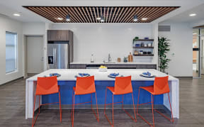a kitchen with a blue island and four orange chairs at Perkins Square Apartments