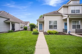 a row of houses with a grassy yard and a sidewalk