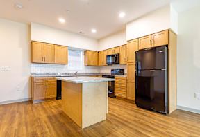 A kitchen with wooden cabinets and a black refrigerator.