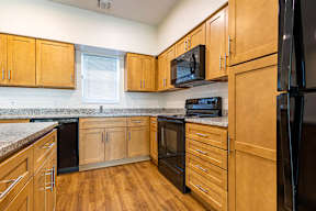 A kitchen with wooden cabinets and black appliances.