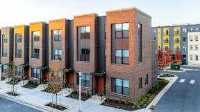 A row of modern brick apartment buildings with trees in front.