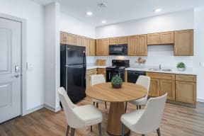 a kitchen with black appliances and a wooden table and chairs