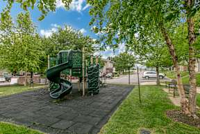 A playground with a green slide and a black mat.