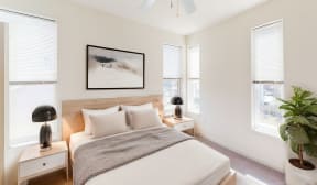 a bedroom with a bed and two windows at Legacy Pointe at Poindexter Apartments & Townhomes