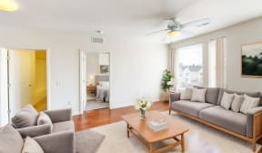 a living room with a couch and a coffee table and a ceiling fan at Legacy Pointe at Poindexter Apartments & Townhomes