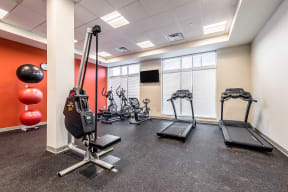 a gym with exercise machines and weights in the corner of a room at Legacy Pointe at Poindexter Apartments & Townhomes